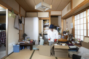 散らかった部屋の整理をする男性作業員